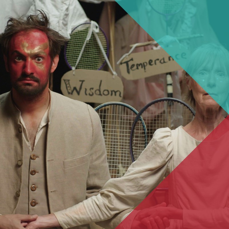 A photograph of actors on a stage. In the foreground an adult man and an older woman  hold hands dressed in dull white linin with signs behind them that say 